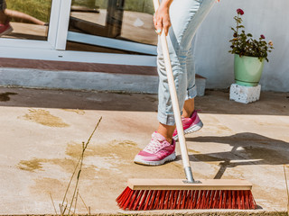 Woman using broom to clean up backyard patio