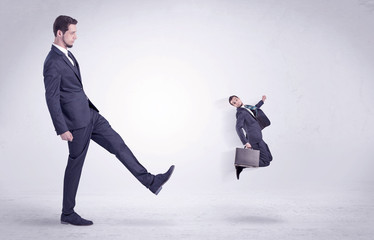 Big man in suit kicking out little himself out with simple white wallpaper
