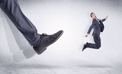 Boss mobbing his worker, illustrated by black shoe kicking small businessman who is flying away in...
