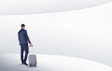 Businessman with back walking in a white waiting room with empty walls around
