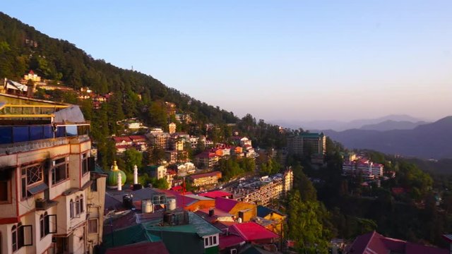 Panning shot of shimla cityscape at dusk with purple skies and golden light. Shot from the famed mall road shows the beautiful panorama post a clear day.