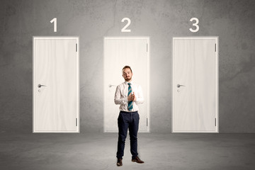 Businessman in grey room with three numbered white  door behind his back
