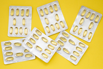 Cod liver oil omega 3 capsules on the yellow background