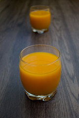 Two bottles of orange juice on the dark wooden background