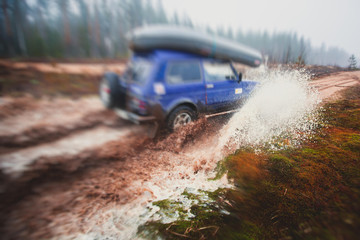 Suv offroad 4wd car rides through muddy puddle, off-road track road, with a big splash, during a jeeping competition