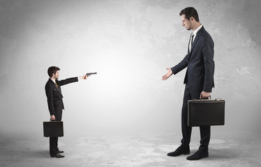Tiny businessman with gun shooting giant fearful businessman
