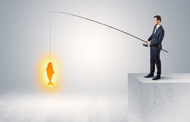 Young businessman fishing golden fish from the top of a building

