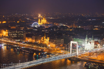 Fototapeta na wymiar Beautuful super-wide angle aerial night view of Budapest, Hungary, with Danube river, Parliament building and scenery beyond the city, seen from observation point of Gellert Hill