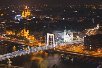 Fototapeta premium Beautuful super-wide angle aerial night view of Budapest, Hungary, with Danube river, Parliament building and scenery beyond the city, seen from observation point of Gellert Hill