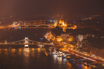 Fototapeta na wymiar Beautuful super-wide angle aerial night view of Budapest, Hungary, with Danube river, Parliament building and scenery beyond the city, seen from observation point of Gellert Hill