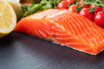 piece of salmon fillet with vegetables on gray slate background