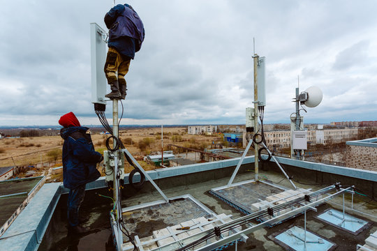 Industrial climbers -workers- without helmets, body climbing harness and uniform work at height for instaling communication equipment and antenna.