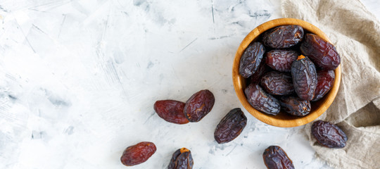 Delicious dates in a wooden bowl. - obrazy, fototapety, plakaty
