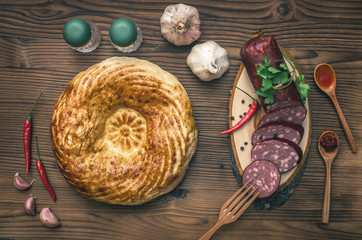 Sausage snag, pita bread, bagels, tomatoes, garlic, chilli pepper and greenery with fennels, dill and parsley on wooden table background.