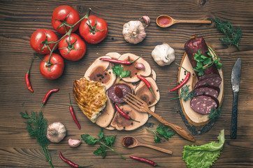 Sausage snag, pita bread, bagels, tomatoes, garlic, chilli pepper and greenery with fennels, dill and parsley on wooden table background.