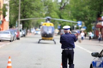 Policjant rozmawia przez telefon przy śmigłowcu ratunkowym w centrum miasta Opola.