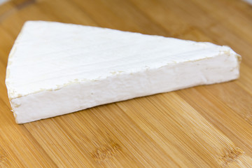 Brie cheese on wooden board. Side view.