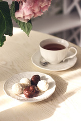 Sunlit dining table with flowers, tea and sweets