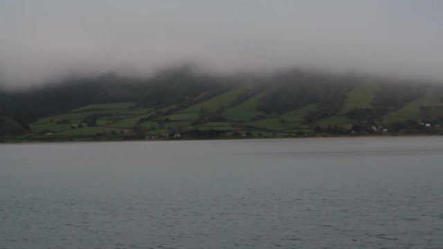 Misty lake and green fields covered by fog