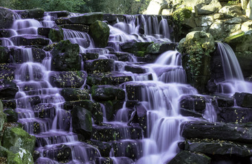 The ornamental Cascade waterfall with purple water in Virginia Water, Surrey, UK