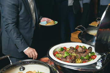 Catering buffet food indoor in luxury restaurant with meat colorful fruits and vegetables. People at a banquet taking different food. Colleagues Buffet Party Brunch Dinning Concept