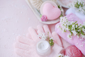 spa hand care, sea salt, cream and gloves. The flowers are white. Pink background. Place for text