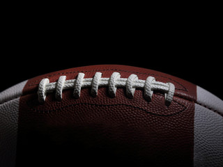 Closeup of an American Football Game Ball Against a Black Background