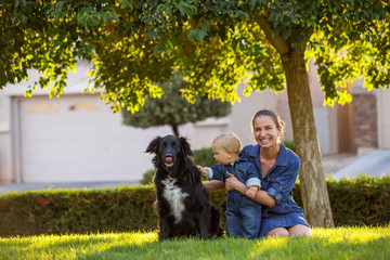 Naklejka na ściany i meble A mother with baby son and black dog in green neighborhood