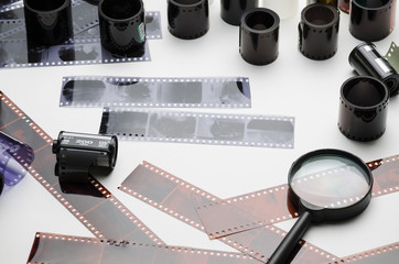 Photonegatives, film and magnifying glass on white background