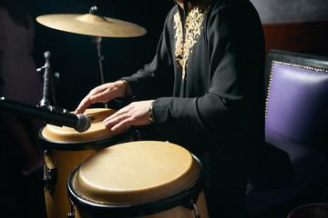 Man hands playing music at djembe drums. Musician playing congas, close-up. Rhythm of Africa, Bongo...