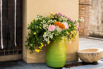 Green vase with wild flowers on a city street in Kyoto, Japan. Copy space for text.