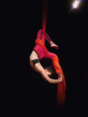 Aerial silks dancer in red on black background