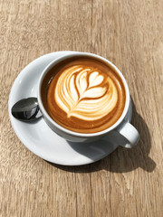 Outdoor Vintage mood, Cappuccino on top with heart flower latte art lay on wood texture table. Love latte art on coffee cappuccino . Heart and flower latte art pattern.