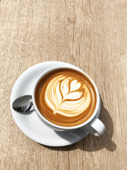 Outdoor Vintage mood, Cappuccino on top with heart flower latte art lay on wood texture table. Love latte art on coffee cappuccino . Heart and flower latte art pattern.