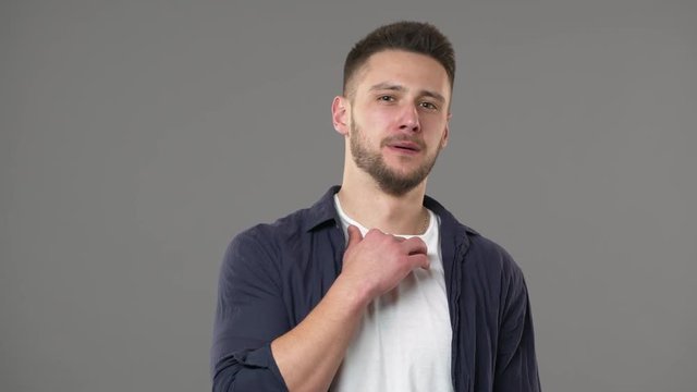 Portrait of outraged man in casual clothing having vomit reflection and feeling disgust or aversion, isolated over gray background. Concept of emotions