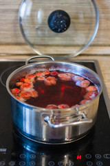 Boiling strawberry compot  in metall pan on the kitchen table