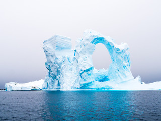 Arch shaped iceberg in Pleneau Bay iceberg graveyard west of Antarctic Peninsula, Antarctica - obrazy, fototapety, plakaty