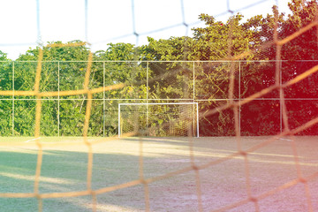 soccer posts in park, field is partially covered in the shadow. Trees in the background are in the sun. Rio de Janeiro, Brazil. Colored light leak filter applied