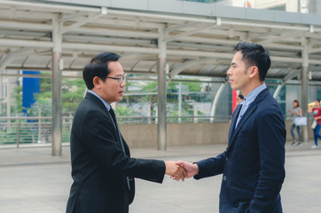 attractive business man shaking hand for complete deal together business successful at outdoor in city. teamwork concept. partnership concept and dealership concept.