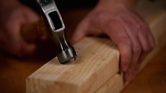 Attempting to hammer a nail into fresh lumber but bending the nail by mistake