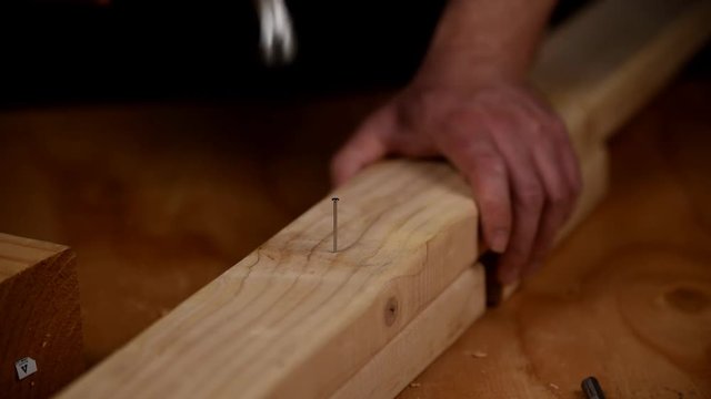 Hammering a nail into fresh lumber while zooming in