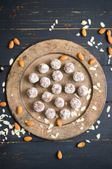 Raw vegan chocolate sweet balls with almonds, cashew, walnuts, nuts, cocoa powder, coconut, dates, oil on vintage moroccan plate and dark background. Closeup view. Vegetarian healthy food concept.