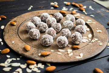 Raw vegan chocolate sweet balls with almonds, cashew, walnuts, nuts, cocoa powder, coconut, dates, oil on vintage moroccan plate and dark background. Closeup view. Vegetarian healthy food concept.
