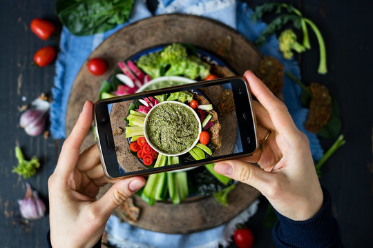 Phone photography of food. Woman hands take photo of lunch with smartphone for social media. Buddha bowl with fresh vegetables. Raw vegan vegetarian healthy dinner 