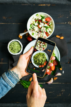 Phone photography of food. Woman hands take photo of lunch with smartphone for social media. Raw vegan zucchini spaghetti with avocado sauce. vegetarian healthy dinner 