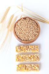 muesli bar. whole grain muesli bar, wheat grains in a wooden cup and wheat ears on a light background. healthy eating. Vegan food