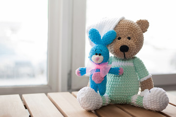 Brown stuffed animal teddy bear and small knitted blue rabbit on the wood. Copy space