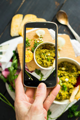 Phone photography of food. Woman hands take photo of lunch with smartphone for social media. Dip or spread. Raw vegan vegetarian healthy dinner 