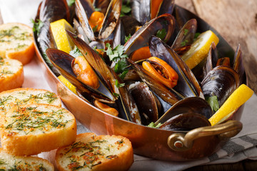 French mussels with lemon, parsley and garlic close-up in a copper pot and toast. horizontal - obrazy, fototapety, plakaty