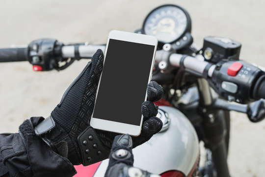 Fototapeta biker riding motorbike and holding smart phone